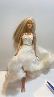 Front view of Barbie doll in white satin feather-trim dress