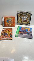 All four items laid out: Pokemon FireRed booklet, WWE John Cena patch card, Yu-Gi-Oh rulebook, Destruction Derby 2 manual