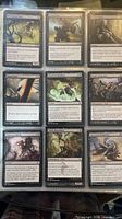 Nine black Magic cards including Doom Blade and Duress in binder page