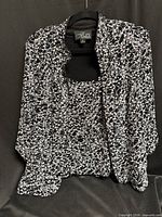 Two-piece blouse set on hanger showing jacket over shell