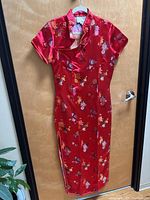 Full view of red embroidered Chinese satin dress hanging on door