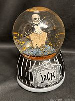 Front view of snow globe showing Jack Skellington, tombstone, base design