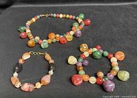 Necklace and two bracelets laid flat on black background