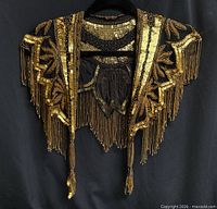 Full front view of gold sequin and beaded shoulder collar with fringe on hanger