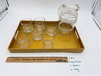 full lot showing pitcher, six glasses on yellow tray with ruler for scale