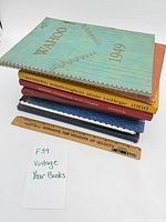 Stack of seven yearbooks with rulers, showing binding types and spine text