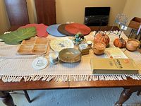Entire lot displayed on dining table showing placemats, tray, ceramics, pumpkins, candles, easels, HOHIYA box