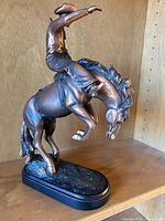 Front left view of bronze-tone cowboy on rearing horse figurine on black base