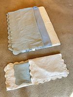 Folded bedspreads showing light blue and ivory embossed patterns