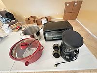 All four items laid out on table: stock pot, toaster oven, slow cooker, coffee maker