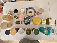 Overhead view showing quantity and variety of candles in jars, tins and bowl