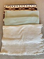 Stack of four blankets showing Southwestern, sage green and cream knit examples