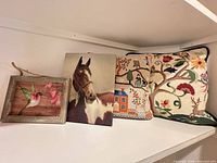 Group shot of two needlepoint pillows, horse canvas, hummingbird framed print