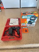 Craftsman drill in red case, Black & Decker Mouse box and sanding pad pack on counter