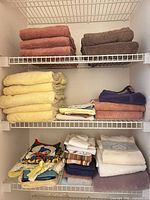 Full view of closet shelves showing multiple stacks of towels in assorted colours and sizes