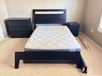 Overall view of bed frame, mattress, dresser and nightstand