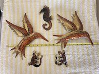 Front view of all five mixed metal wall art pieces laid out on towel with measuring tape