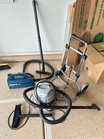 Overall lot showing both vacuums, hand truck, hoses, tools