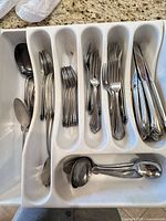 Drawer insert holding assorted stainless flatware pieces