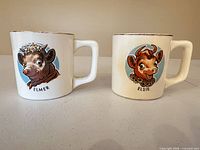 Both mugs front view showing Elsie and Elmer graphics and overall condition