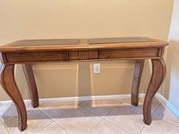Front view of console table highlighting glass inset top and cabriole legs