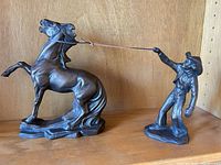 Horse and cowboy resin figurines connected by rope