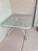 Overall view of square white metal patio table on patio