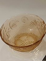 Side perspective of pink-amber depression glass bowl showing starfish and seashell relief and scalloped rim