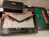 All three Scrabble games: Deluxe French edition box, travel zip case, Scrabble Original box