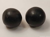 Two black spherical jiwaya stone balls on white background