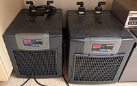 Front view of both Arctica chillers side by side showing grilles, power cords, and top hose fittings