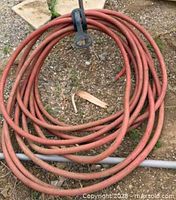 Full view of coiled red hose on ground