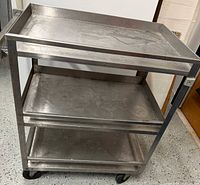 Full view of stainless steel cart showing three shelves and casters