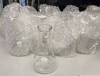 Single Pyrex flask in front of bubble-wrapped flasks