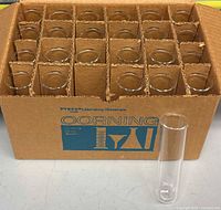 Open Corning box showing 24 test tubes in corrugated partitions, one tube placed in front for scale