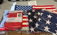 Four folded/packaged American flags showing stars-and-stripes and blue canton designs