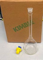 Flask with stopper beside original KIMBLE box and yellow protective cap
