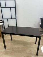 Overall view of black rectangular table on light wood floor