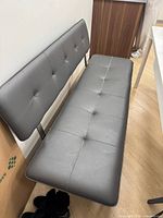 Full view of grey upholstered bench showing backrest, seat, legs, and overall condition