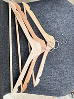 Stack of three wooden hangers showing mixed wood tones, metal hooks, and detached pant bar