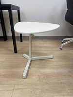 Full view of white adjustable laptop stand showing triangular top, column, and Y base