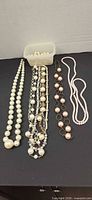 group of four necklaces and container of beads