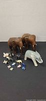 Group view of all elephant figurines including two large wood, one porcelain Casades and assorted minis