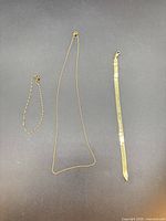 Necklace and two bracelets laid flat on dark background