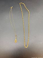 Both gold necklaces laid flat