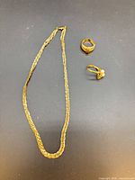 Necklace and two rings laid out on surface