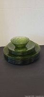 Full stack of green glass dinnerware with bowl on top