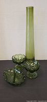 Group shot of olive glass vase with three pressed glass dishes