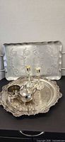 All items grouped: pewter tray at back, silver-plate tray with creamer, sugar bowl and candlesticks
