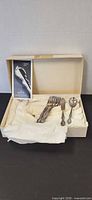 Open box showing flatware pieces and brochure